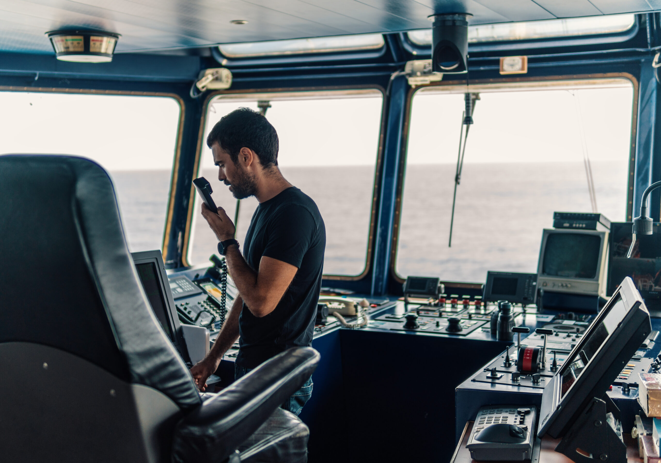Marine navigational officer is reporting by VHF radio during navigation watch. Bridge GMDSS watch
